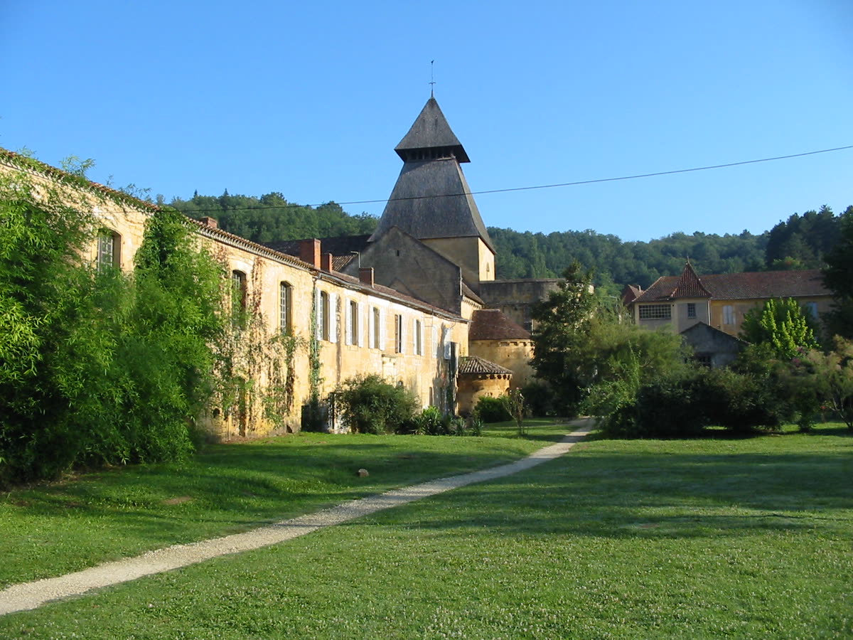 Bâtiments en pierre blonde et clocher pyramidal de l’abbaye de Cadouin, en Périgord